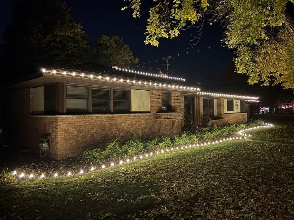 House adorned with festive lights at night, showcasing a warm, inviting outdoor atmosphere.